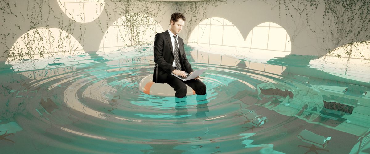 an illustration of a man working on a laptop while floating in a flooded office